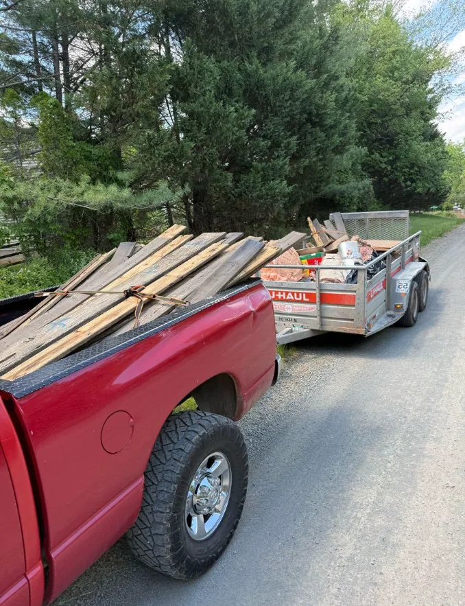 Pickup and utility trailer loaded with old deck lumber and construction debris