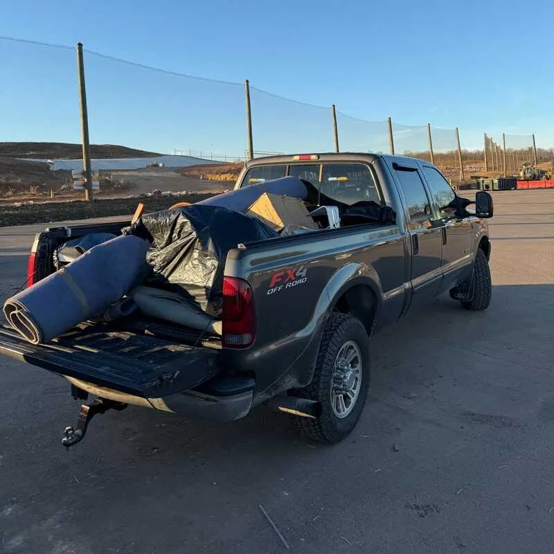 Truck bed packed with rolled carpet, padding and boxes headed to the transfer station